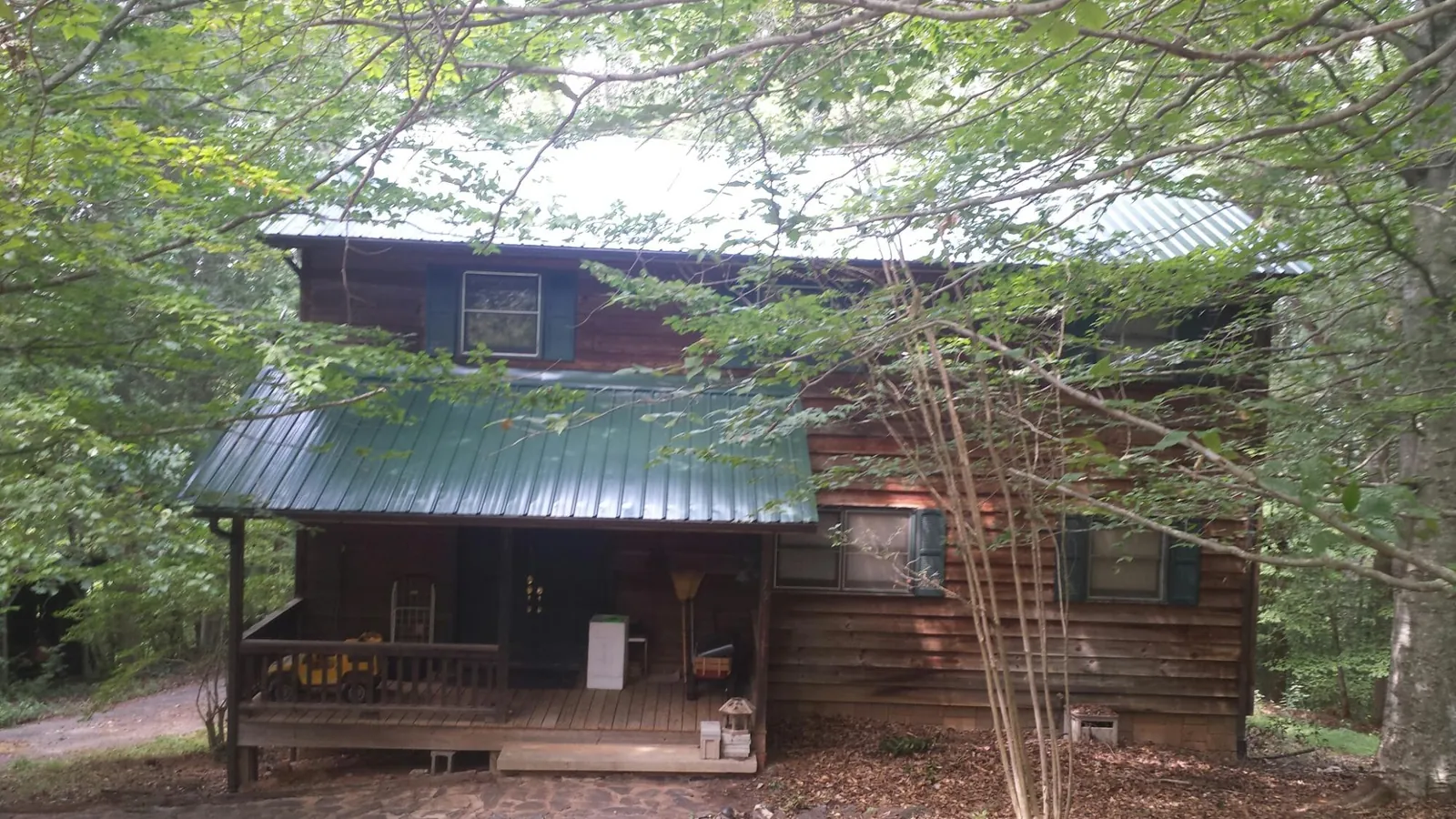 Green metal roof and covered porch on a log cabin in Larkspur