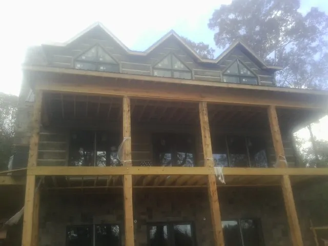 Dormers and porch framing on a large log home under construction — Roof Coating work by our crew in Larkspur