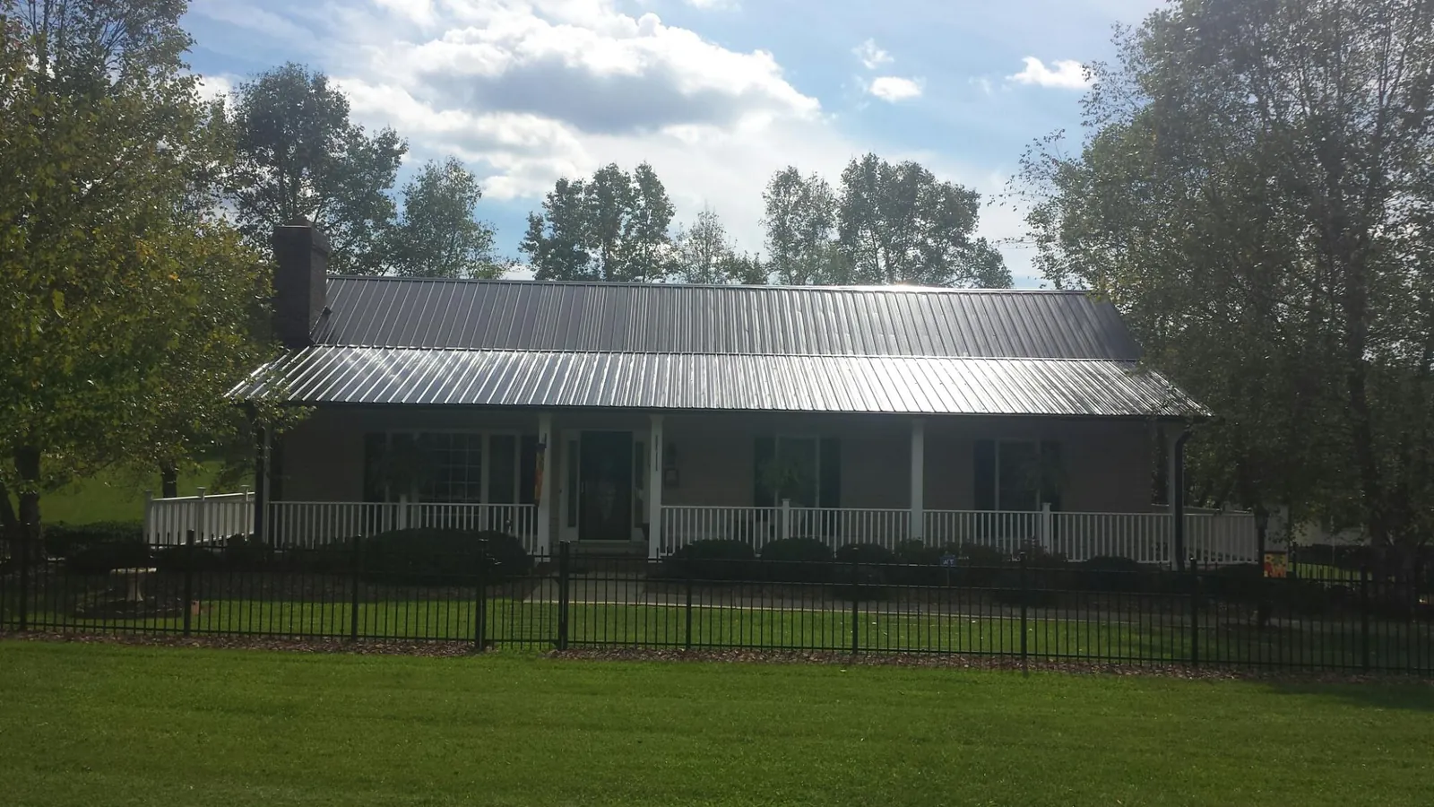 Gray metal roof on a brick ranch with a full width front porch — Gutter Guard Installation work by our crew in Larkspur