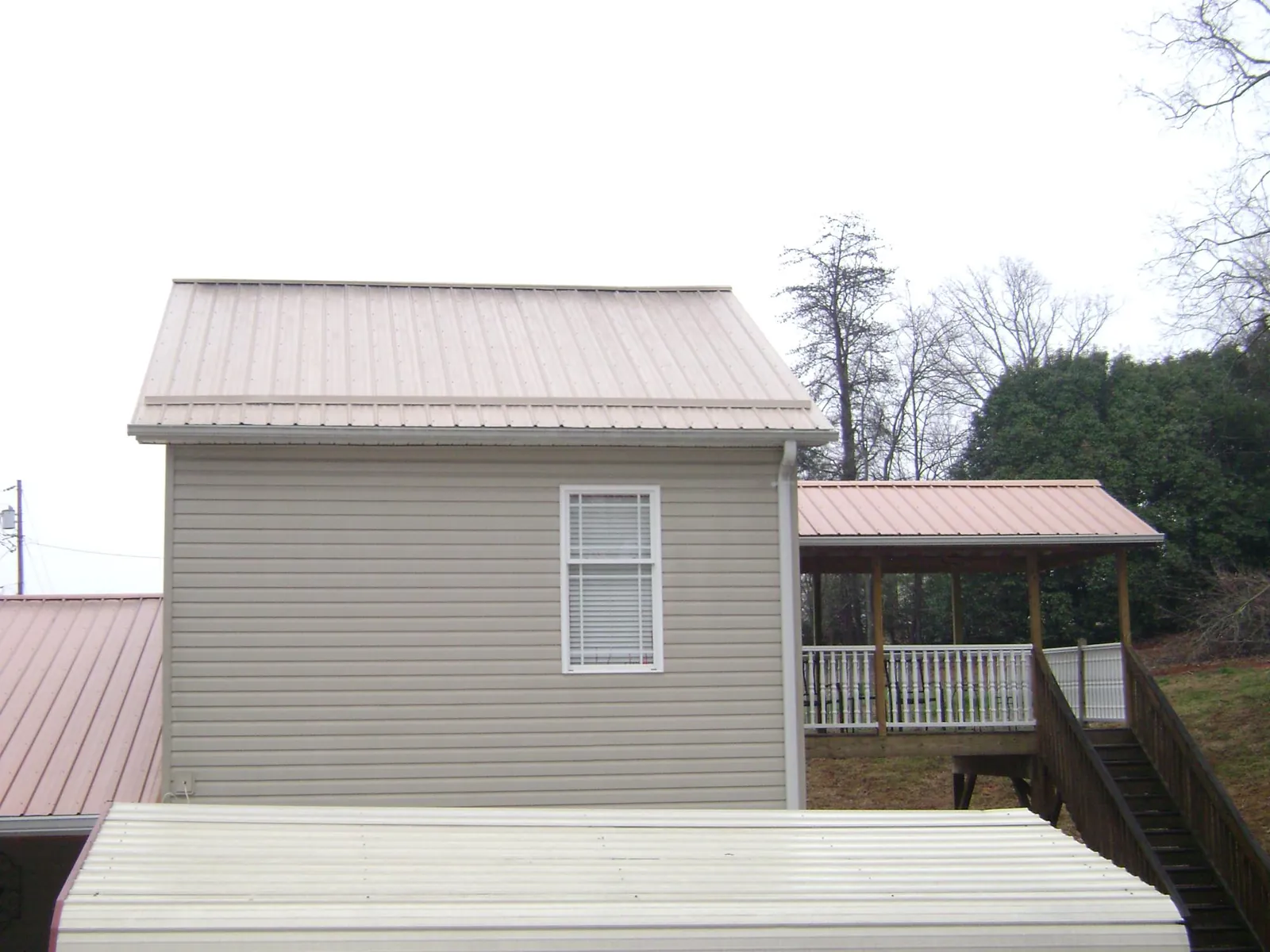 Tan metal roofs on a two story addition and attached porch, from a Roof Replacement job in Larkspur